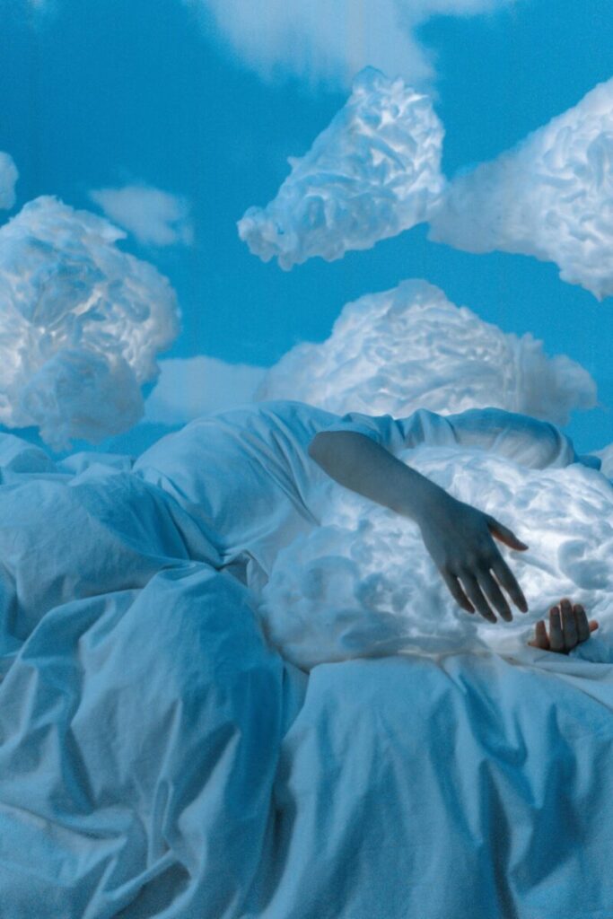 A dreamlike atmosphere with a person lying on a bed, hugging a cloud-like pillow amidst a blue sky backdrop.