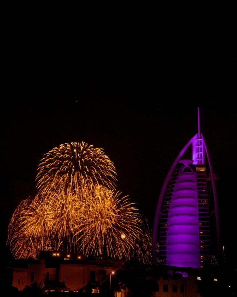 Vibrant fireworks display alongside the illuminated Burj Al Arab at night in Dubai, UAE.